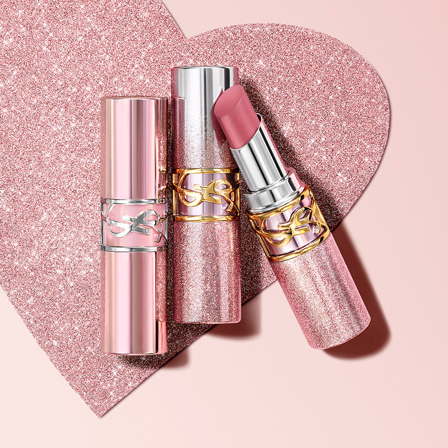 Tre tubetti di rossetto YSL LOVESHINE CANDY GLAZE in edizione limitata (argento e oro rosa glitterato) su uno sfondo a cuore scintillante.