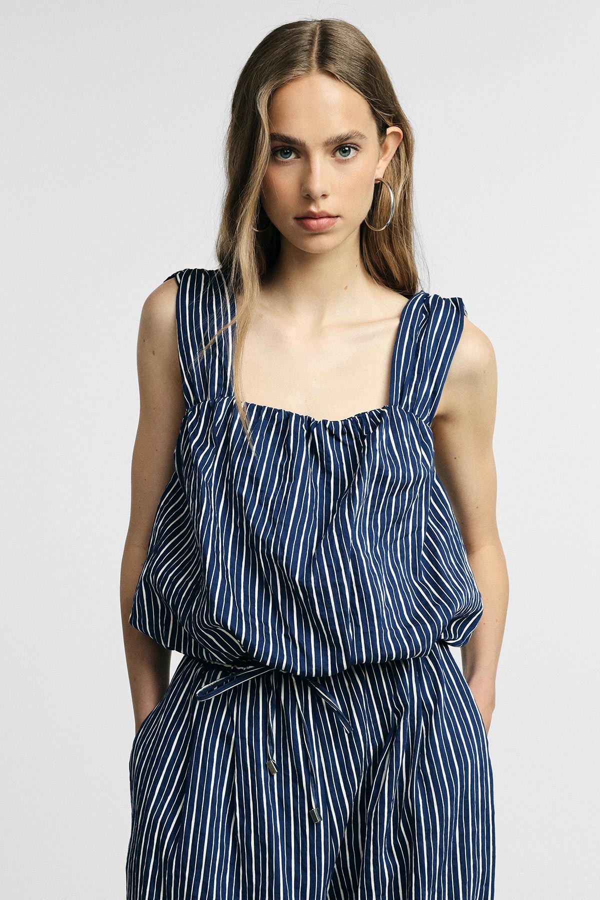 Young woman modelling navy-and-white vertical striped sleeveless top and matching trousers, hands in pockets