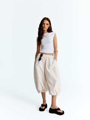 Modella con top bianco e pantaloni larghi 3/4.