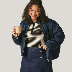 Donna sorridente con giacca blu navy, top a righe e gonna, tiene in mano una tazza di caffè, in piedi davanti a uno sfondo chiaro e semplice.
