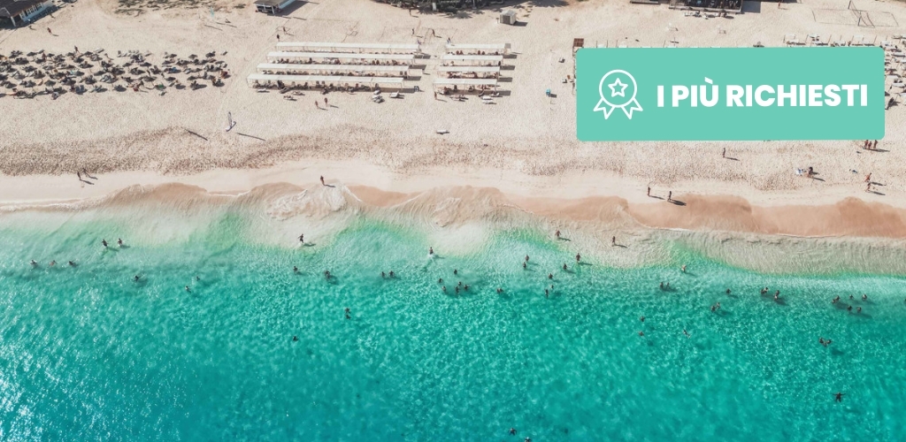 Aerial view of turquoise sea and sandy beach with sunbeds, swimmers and sunbathers along the shore