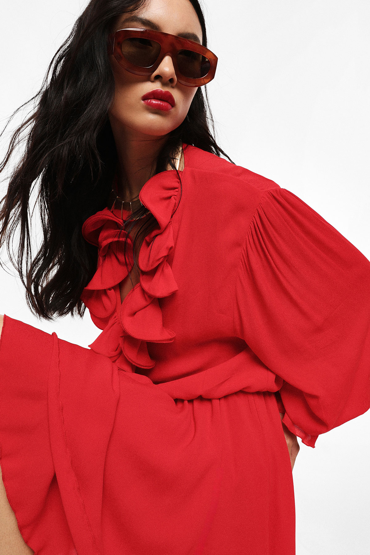 Model wearing red ruffled long-sleeve dress and brown sunglasses, close-up fashion portrait
