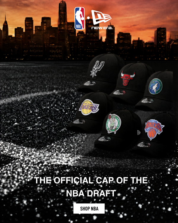 A collection of black New Era caps  against a city skyline at sunset