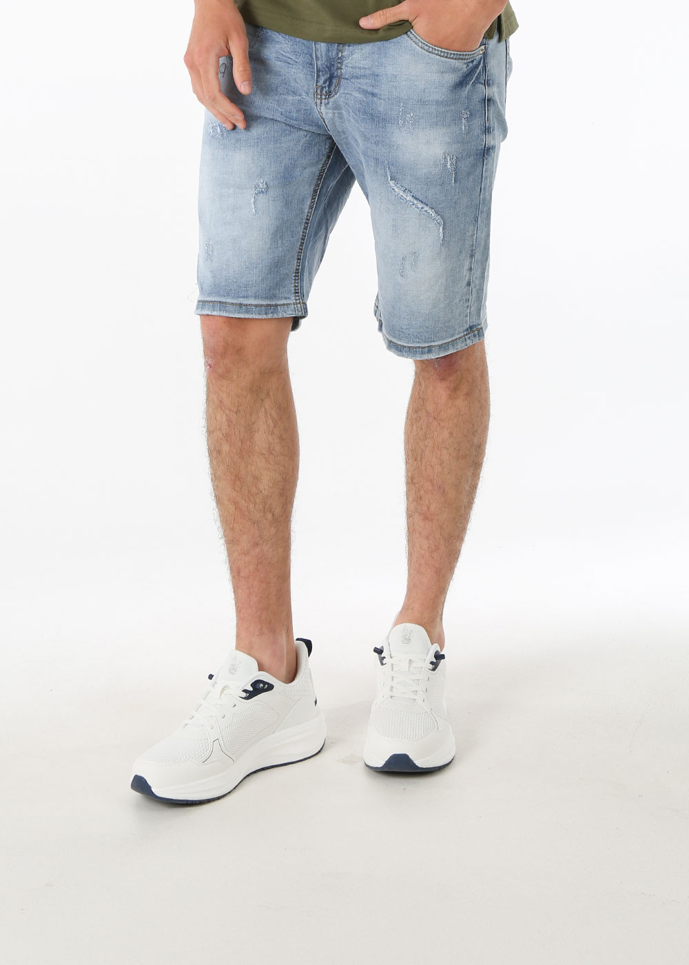 Male model from waist down wearing light distressed denim shorts and white trainers on a plain white background