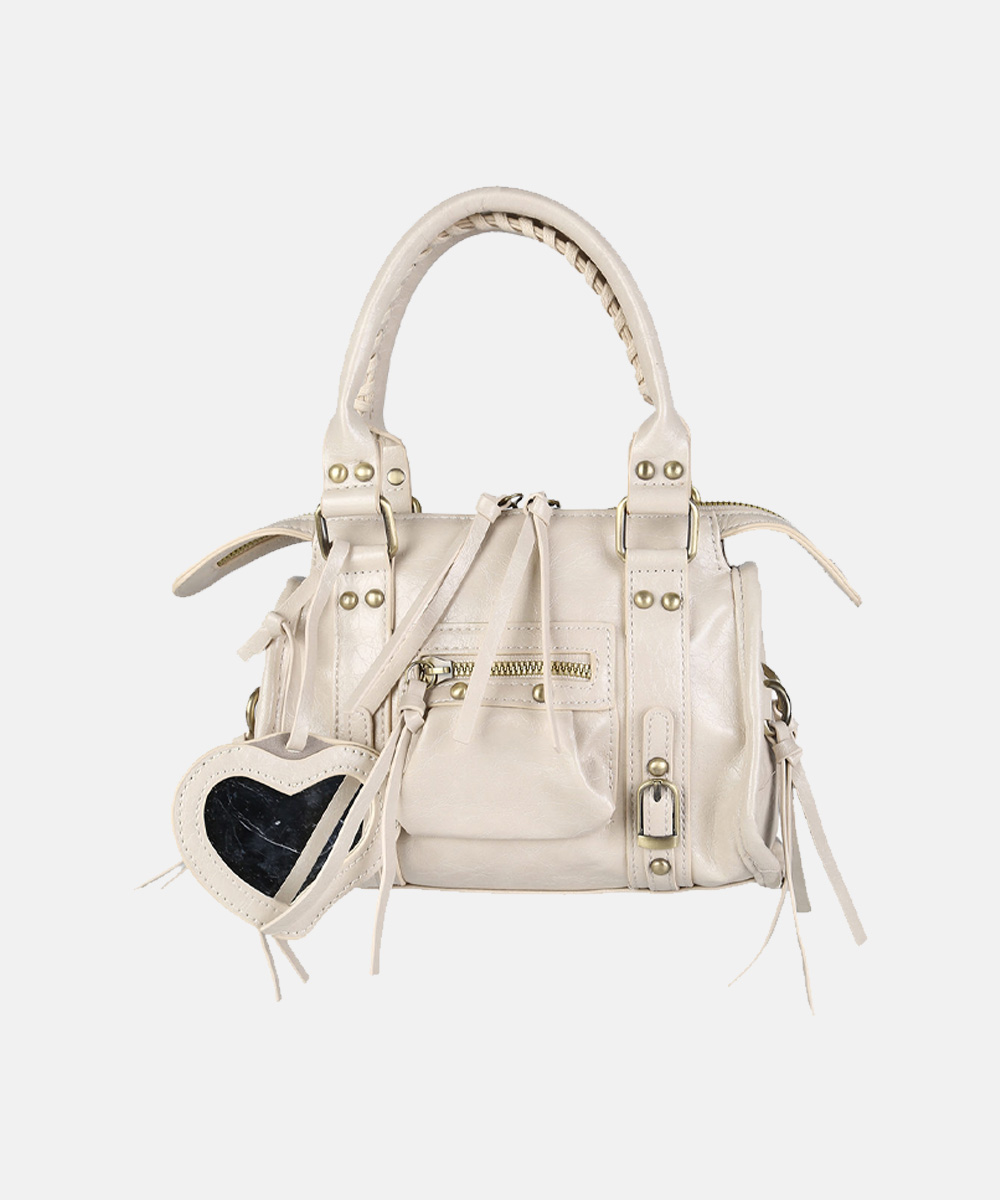 Cream leather satchel handbag with braided top handles, gold hardware, front zip pocket and heart-shaped mirror charm