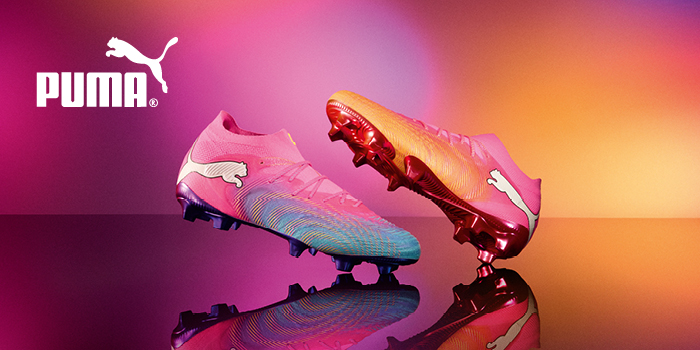 Pink and orange Puma football boots on reflective surface with white Puma logo, colourful gradient background