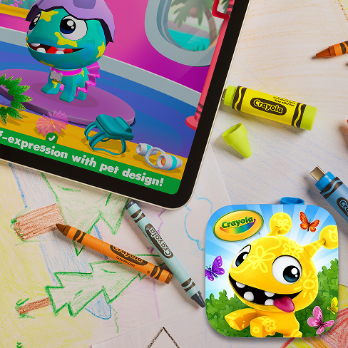 Un tablet che mostra un colorato gioco di design per animali domestici, circondato da pastelli Crayola e un disegno di un bambino, che suggerisce un gioco creativo.