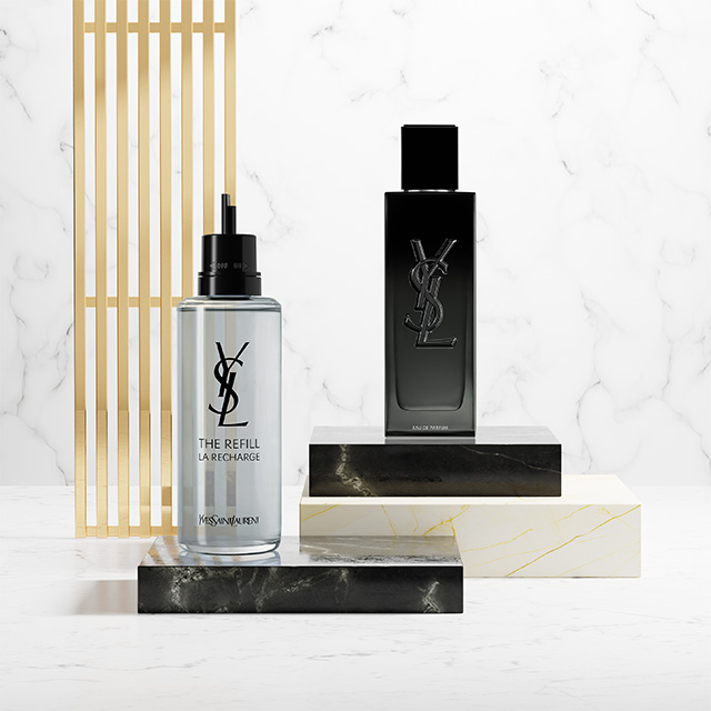 Un flacone di profumo nero YSL MYSLF e la sua ricarica metallica esposti su piedistalli in marmo e pietra nera.
