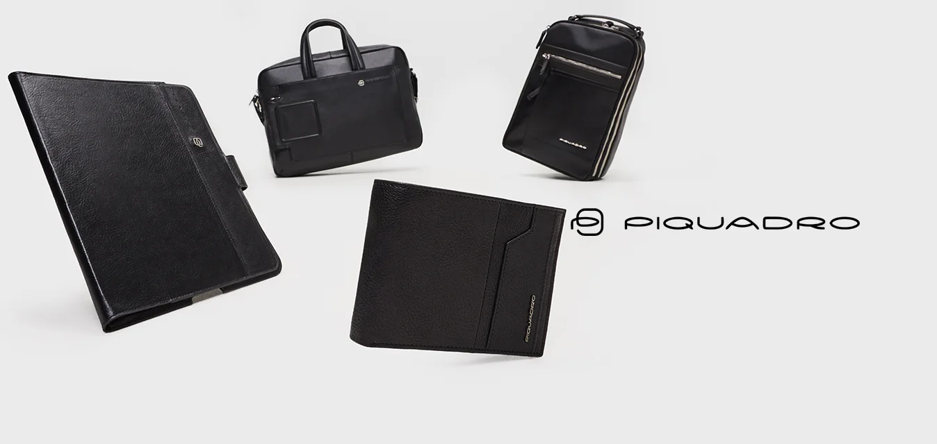 Quattro borse in pelle nera sono esposte: un cartella slim, una valigetta con manico e due zaini con zip e dettagli in contrasto.