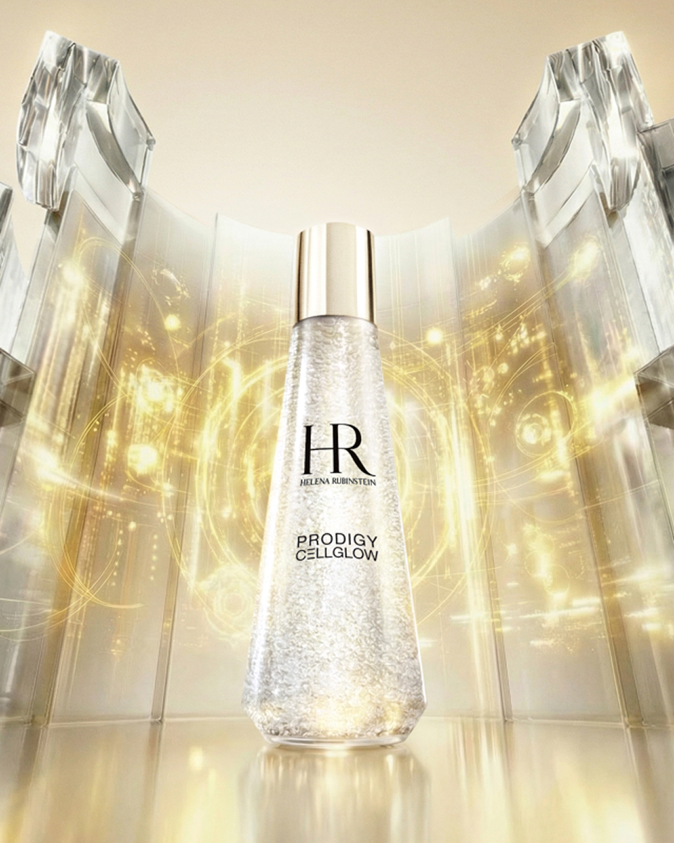 A sleek white bottle of Prodigy Cellglow essence illuminated by warm, golden light.