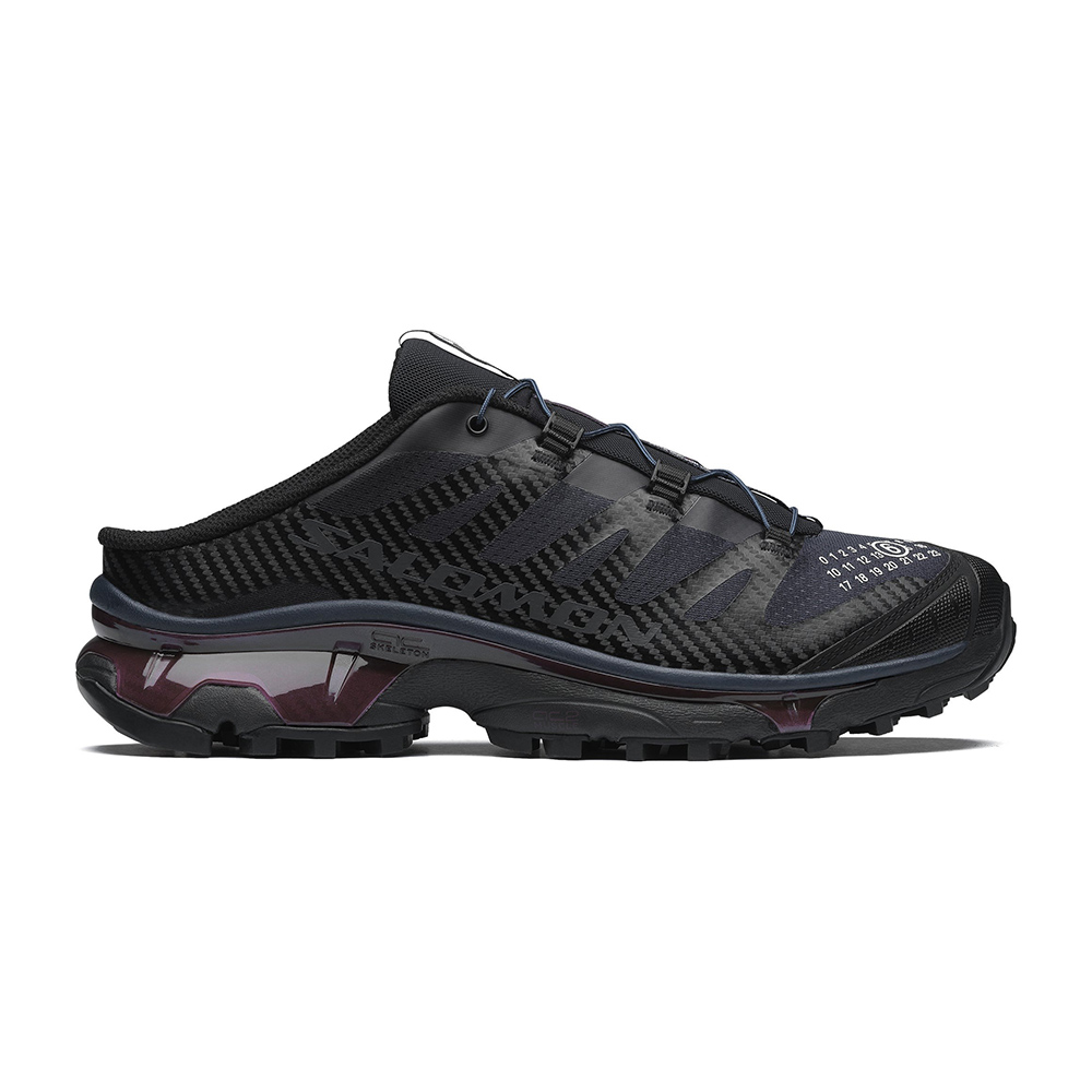 Black slip-on trail running mule with carbon-pattern upper, elastic lacing, lugged sole and maroon translucent midsole detail