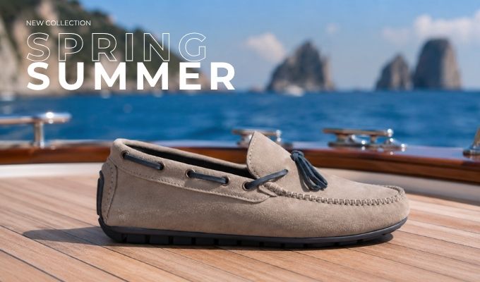 Beige suede tassel loafer on a wooden yacht deck with blue sea and rocky islets in the background — Spring/Summer collection