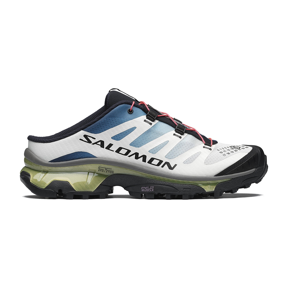 Salomon low-cut trail running shoe in white and blue with black toe, green translucent midsole and aggressive lugged outsole, side view