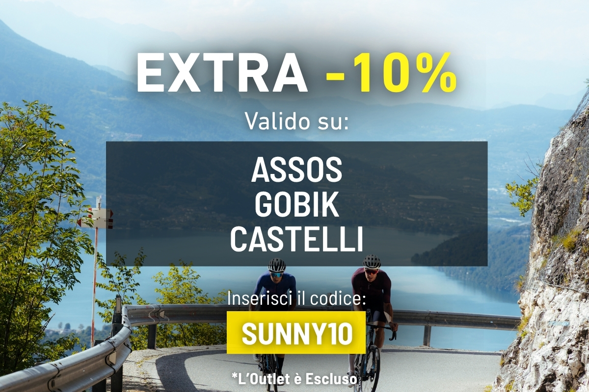 Two cyclists on a mountain road above a lake with promotional banner offering EXTRA -10% valid on Assos, Gobik, Castelli — code SUNNY10