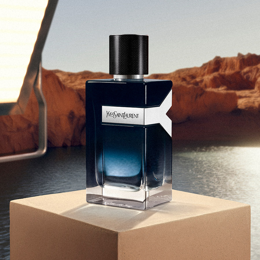 Un flacone di YSL Y Eau de Parfum esposto su un blocco di pietra di fronte a un canyon desertico.