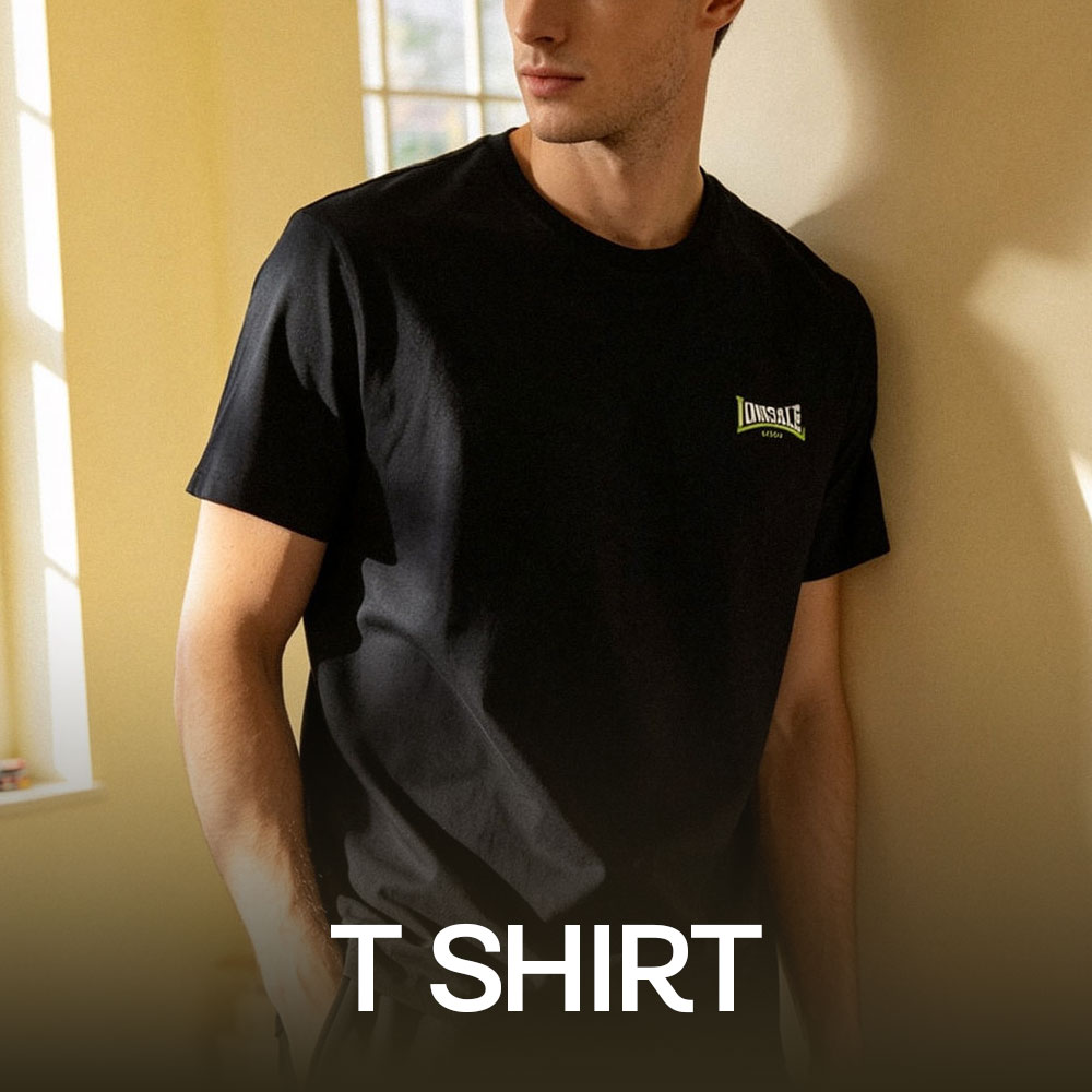 Male model wearing black Lonsdale logo T-shirt by a sunlit window, casual short-sleeve tee in a cropped portrait
