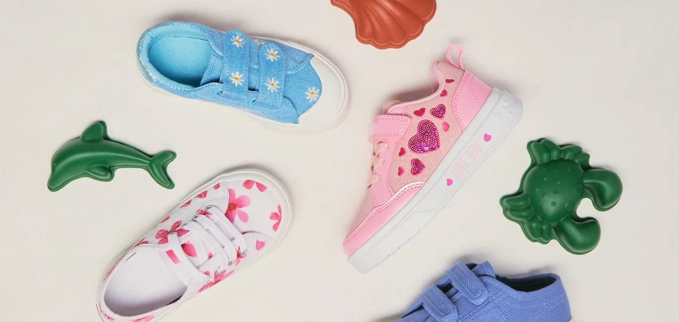 Quattro sneaker colorate per bambini con decorazioni a tema marino circondano giocattoli di animali marini in plastica su uno sfondo semplice.