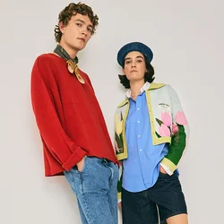 Due giovani adulti in abbigliamento casual e colorato, in piedi su uno sfondo chiaro e semplice con posture rilassate.