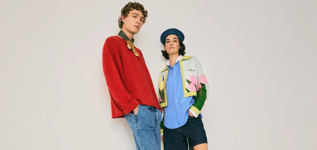 Due giovani adulti in abbigliamento casual e colorato, in piedi su uno sfondo chiaro e semplice con posture rilassate.