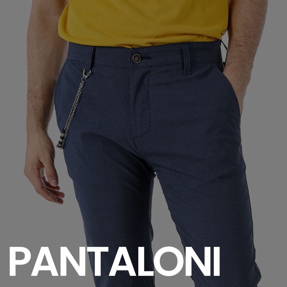Close-up of man wearing navy textured trousers with silver pocket chain and tucked yellow T-shirt, hands near pockets
