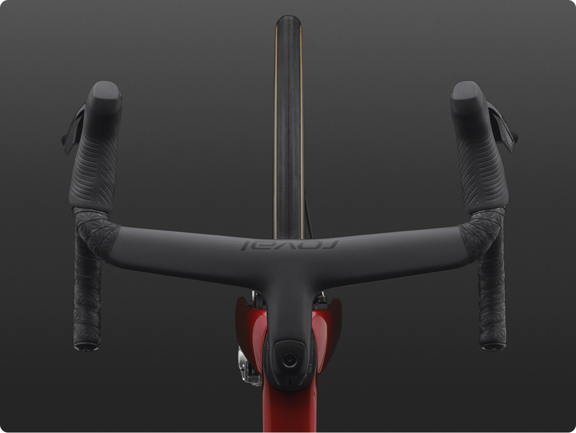 Top-down view of black integrated aero road bike handlebar and stem with textured bar tape, narrow tyre and red frame