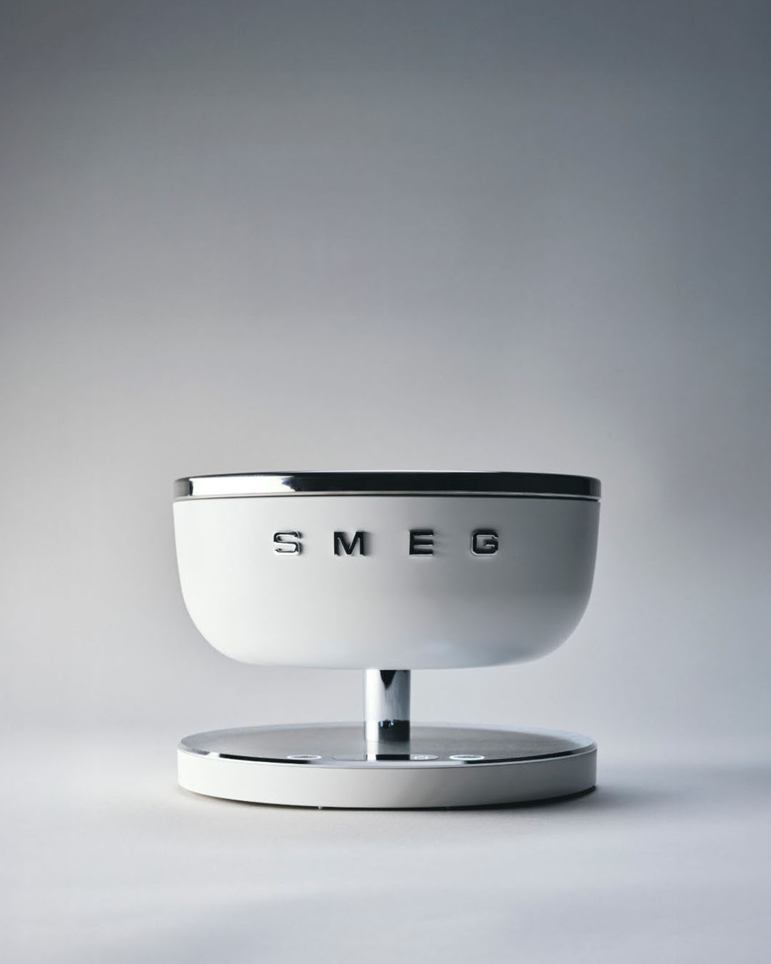 White SMEG digital kitchen scale with chrome trim and pedestal base, front view on neutral background