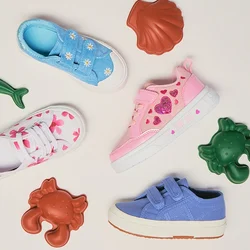 Quattro sneaker colorate per bambini con decorazioni a tema marino circondano giocattoli di animali marini in plastica su uno sfondo semplice.
