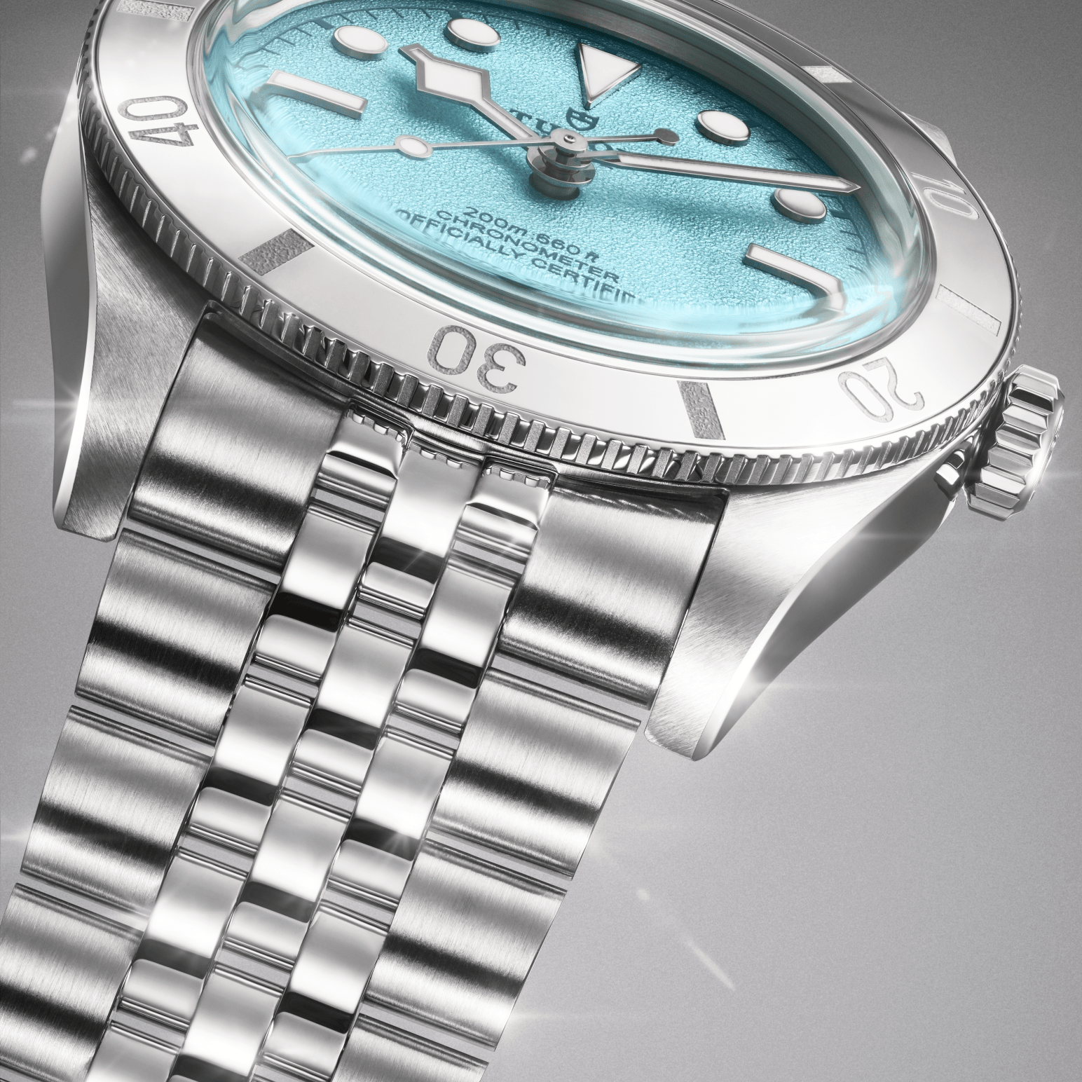 Close-up of luxury stainless-steel wristwatch with turquoise dial, rotating dive bezel, luminous markers and polished bracelet.