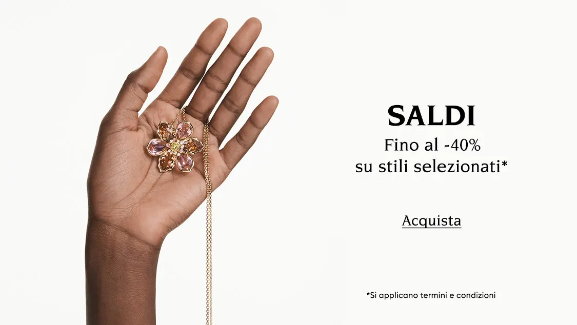 Una mano tiene una collana Swarovski. Il testo recita “SALDI Fino al -40% su stili selezionati* *Si applicano termini e condizioni”. Il pulsante cliccabile recita “Acquista”