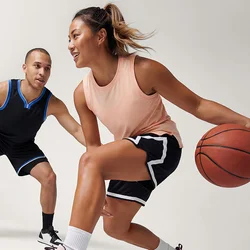 Donna che dribbla una palla da basket mentre un uomo in posizione difensiva la difende su uno sfondo chiaro e uniforme.