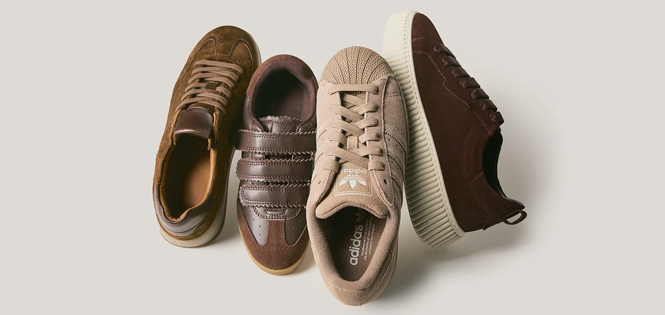 Quattro paia di sneakers: scamosciate marroni, in pelle marrone scuro con strisce, in tela beige con punta testurizzata e in suede borgogna con suola a righe.