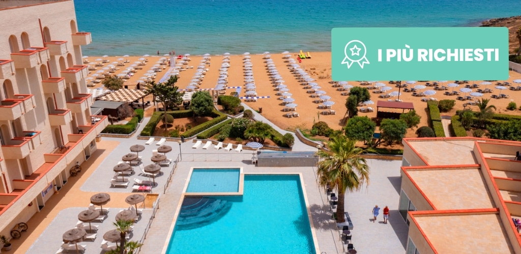 Aerial view of a seaside hotel resort with a turquoise pool, sun loungers and parasols on a sandy beach