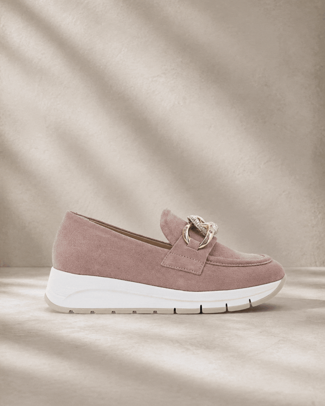 Two women's suede loafers: pink platform with chain detail, and tan driving moccasin with black rubber sole