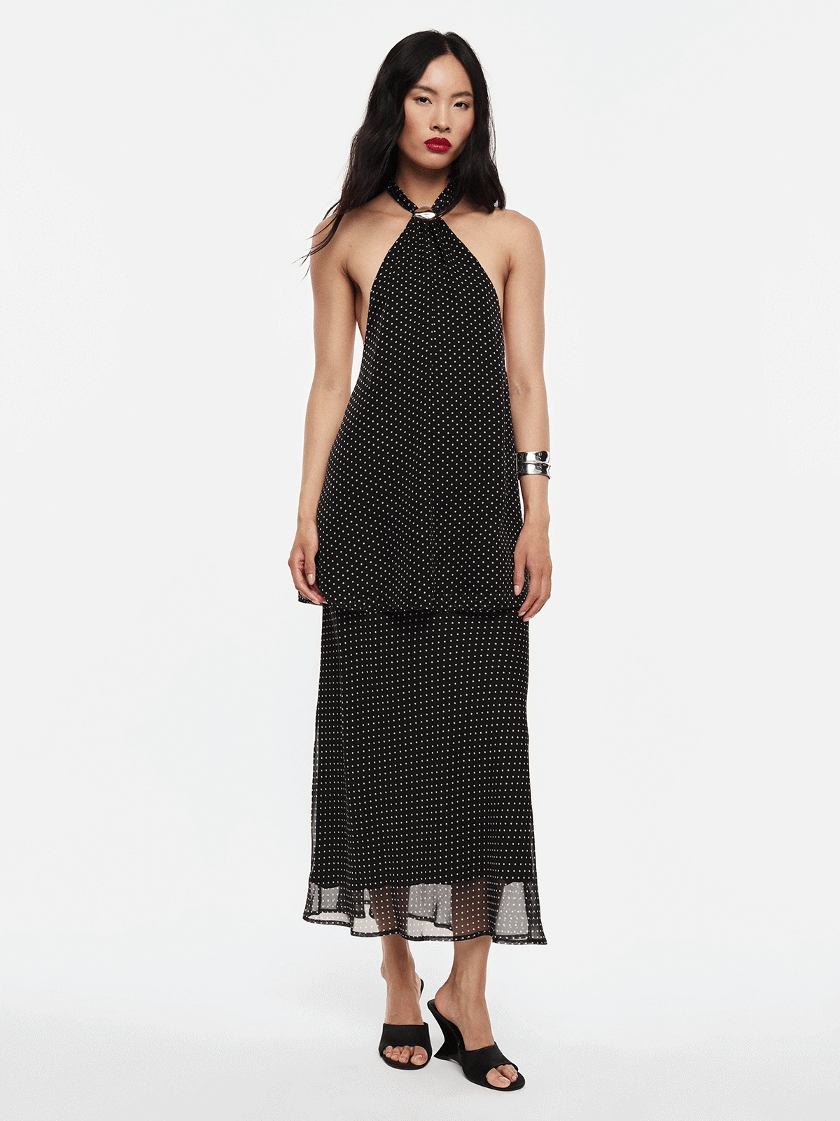 Model wearing black polka-dot halter midi dress with sheer hem, shown front and back, styled with black sandals