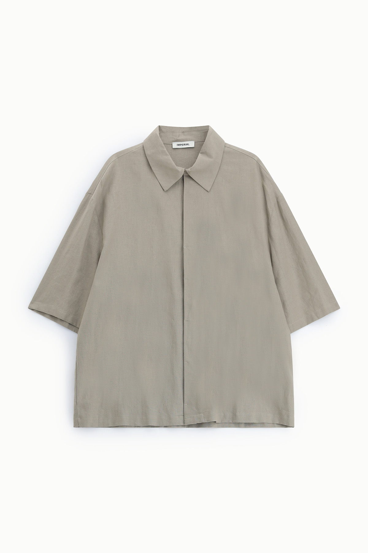 Oversized beige short-sleeve shirt with spread collar and concealed button placket, laid flat on white background