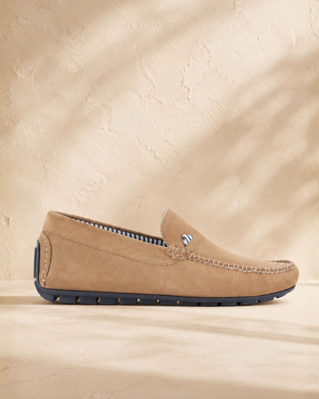 Tan suede men's driving loafer with navy rubber sole and striped inner lining, side profile