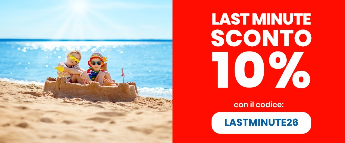 Two children in sunglasses sitting in a sandcastle on a sunny beach by the sea beside a red banner advertising 10% last-minute discount code LASTMINUTE26