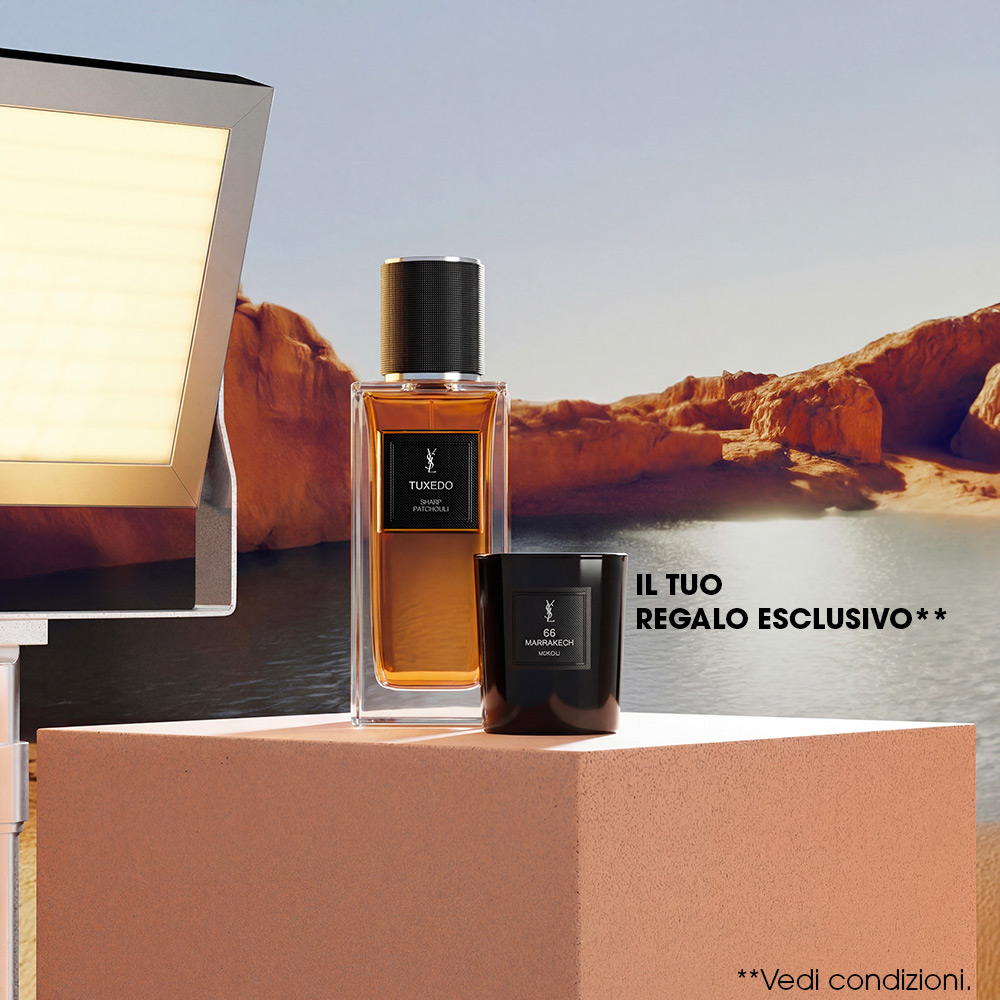Un flacone della collezione "Le Vestiaire des Parfums" di YSL e una candela profumata nera esposti su un piedistallo di pietra di fronte a un lago nel canyon.