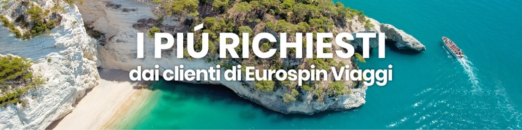 Aerial view of turquoise sea, limestone cliffs and a secluded sandy cove with a small boat; Italian promotional text overlaid