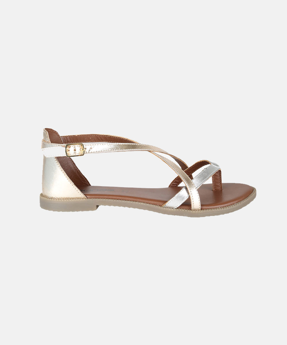 Gold metallic strappy women's flat sandal with ankle buckle and brown footbed, side view on white background