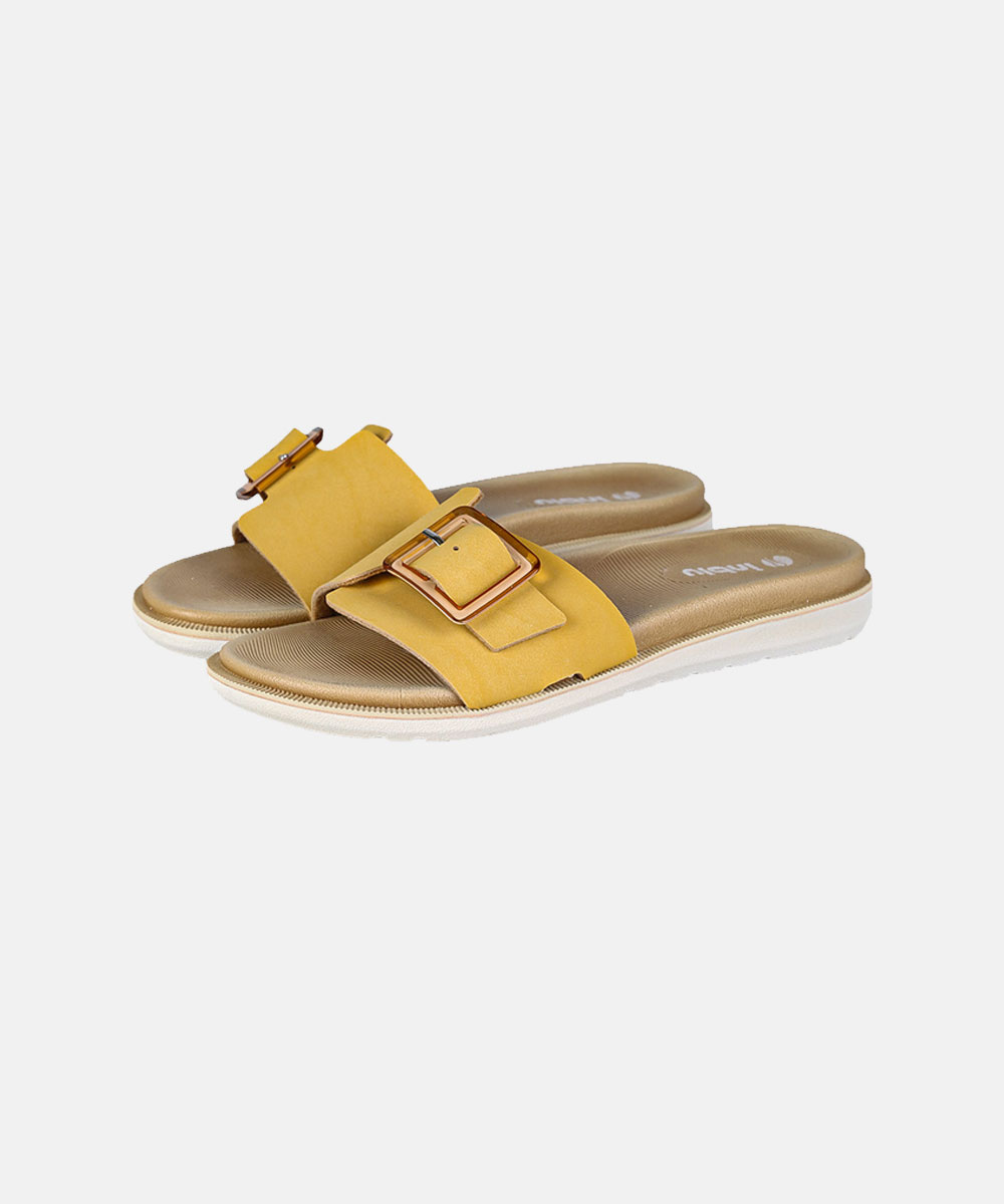Pair of yellow suede slide sandals with gold square buckles and white soles on plain white background