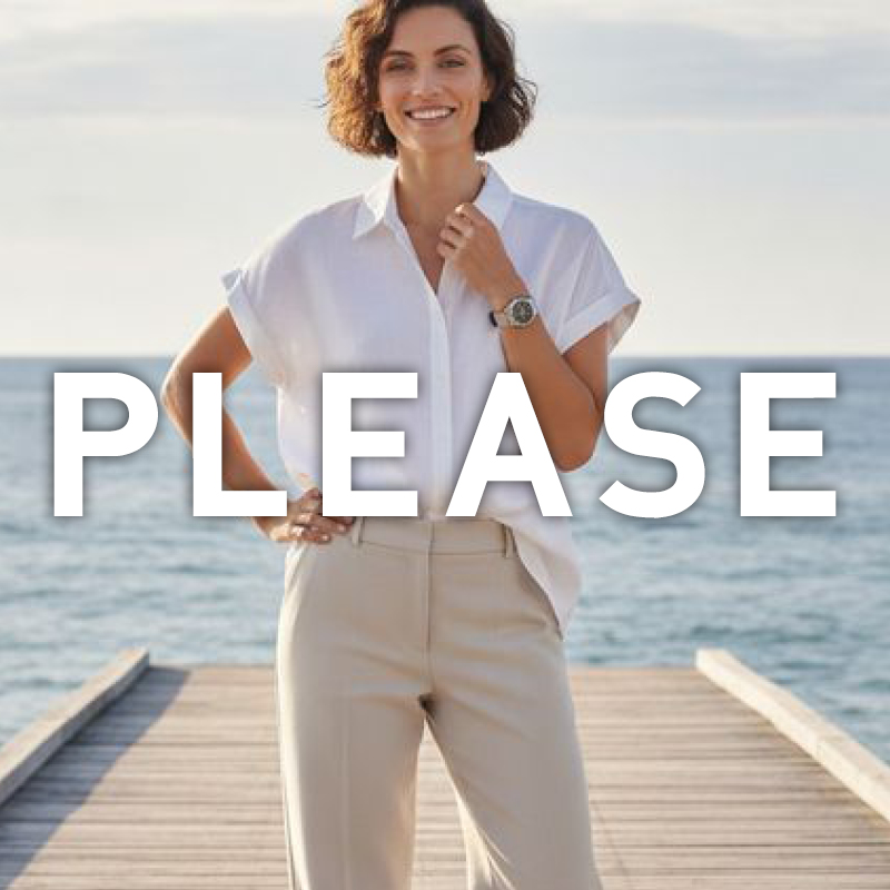 Smiling woman on a wooden jetty by the sea wearing a white blouse and beige trousers, hand on hip, with large 'PLEASE' text overlay