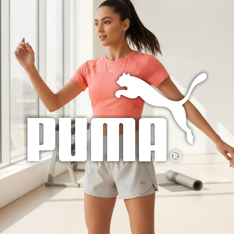 Fit woman in coral Puma crop top and grey shorts exercising in sunlit studio with prominent Puma logo