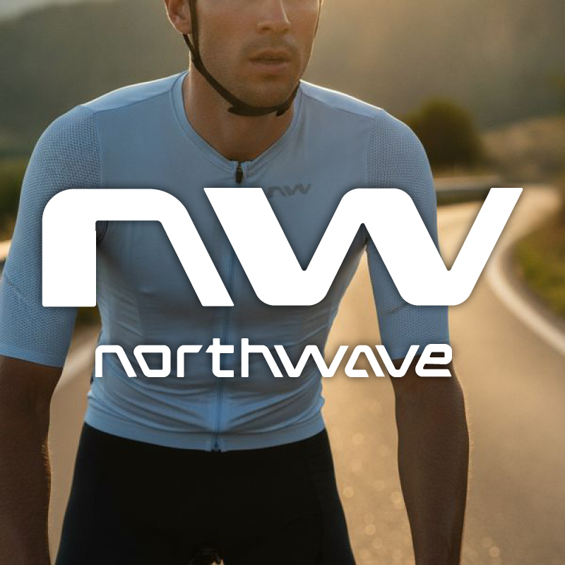 Close-up of cyclist in light-blue cycling jersey on sunlit road with large Northwave logo overlay