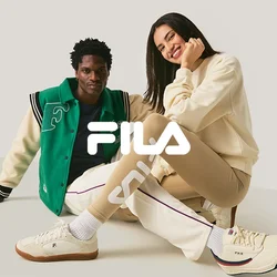 Due persone sedute per terra, una indossa una giacca varsity verde e bianca, l'altra dei leggings beige e una felpa crema, sorridenti.