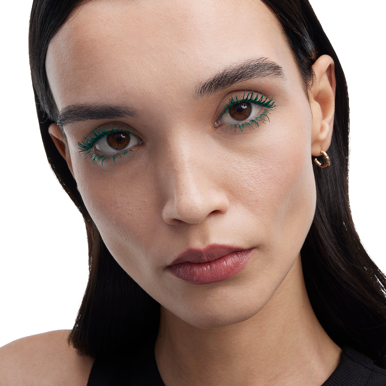 Un ritratto ravvicinato di una donna che mostra un mascara verde vibrante sulle ciglia.