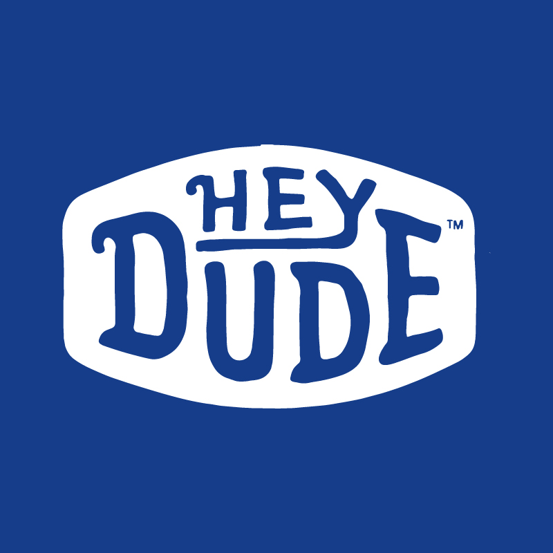 Hey Dude brand logo — blue hand-drawn text inside a white rounded badge on a solid blue background