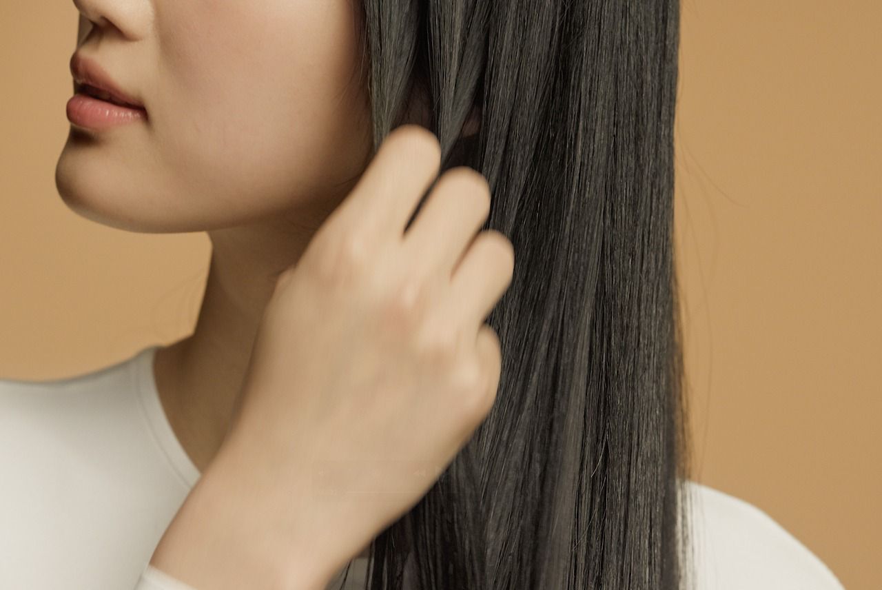 Model smooths Dyson Omega hydrating hair oil through her hair.