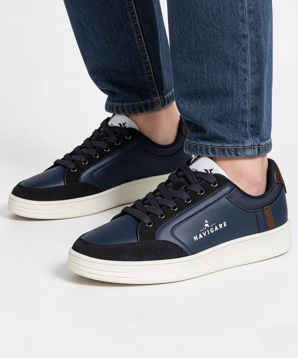 Pair of navy low-top Navigare sneakers with white platform soles and brown heel tab, shown worn with rolled blue jeans