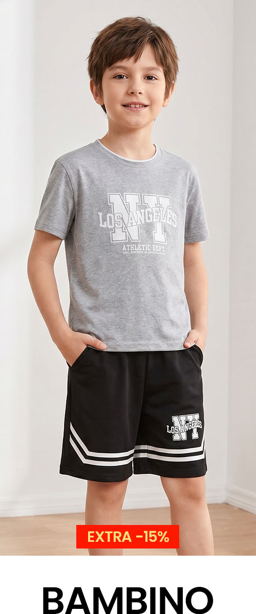 Young boy in grey 'Los Angeles' t-shirt and black sports shorts, hands in pockets, smiling — kids casual summer outfit